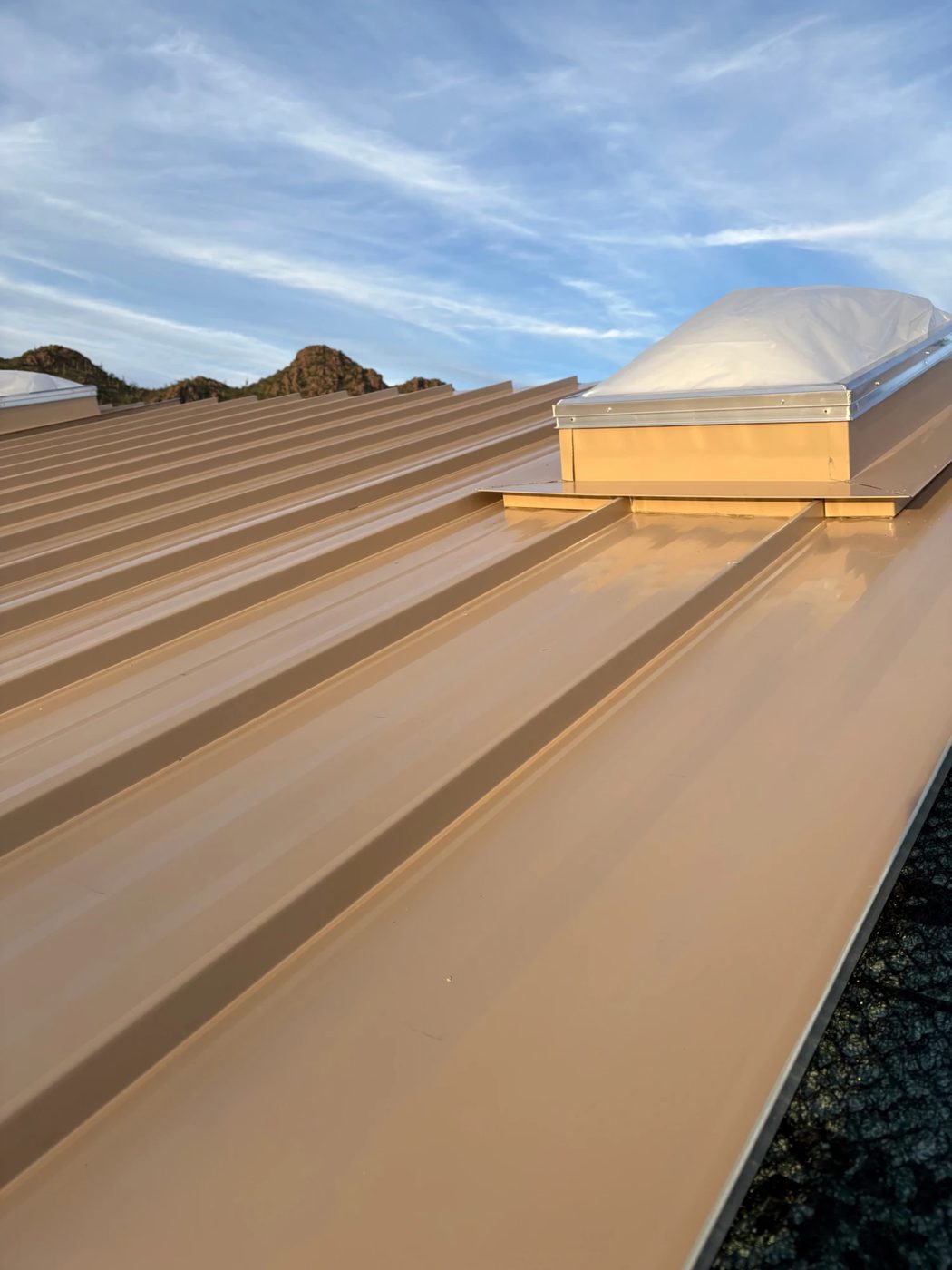Skylight curb and flashing detail on a finished standing-seam metal roof.
