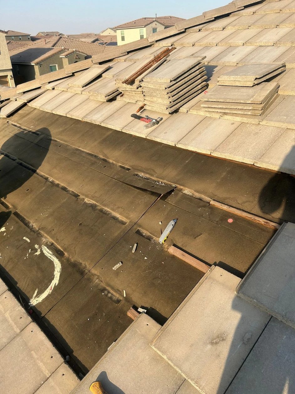 Concrete tile removed and stacked, exposing the worn underlayment beneath