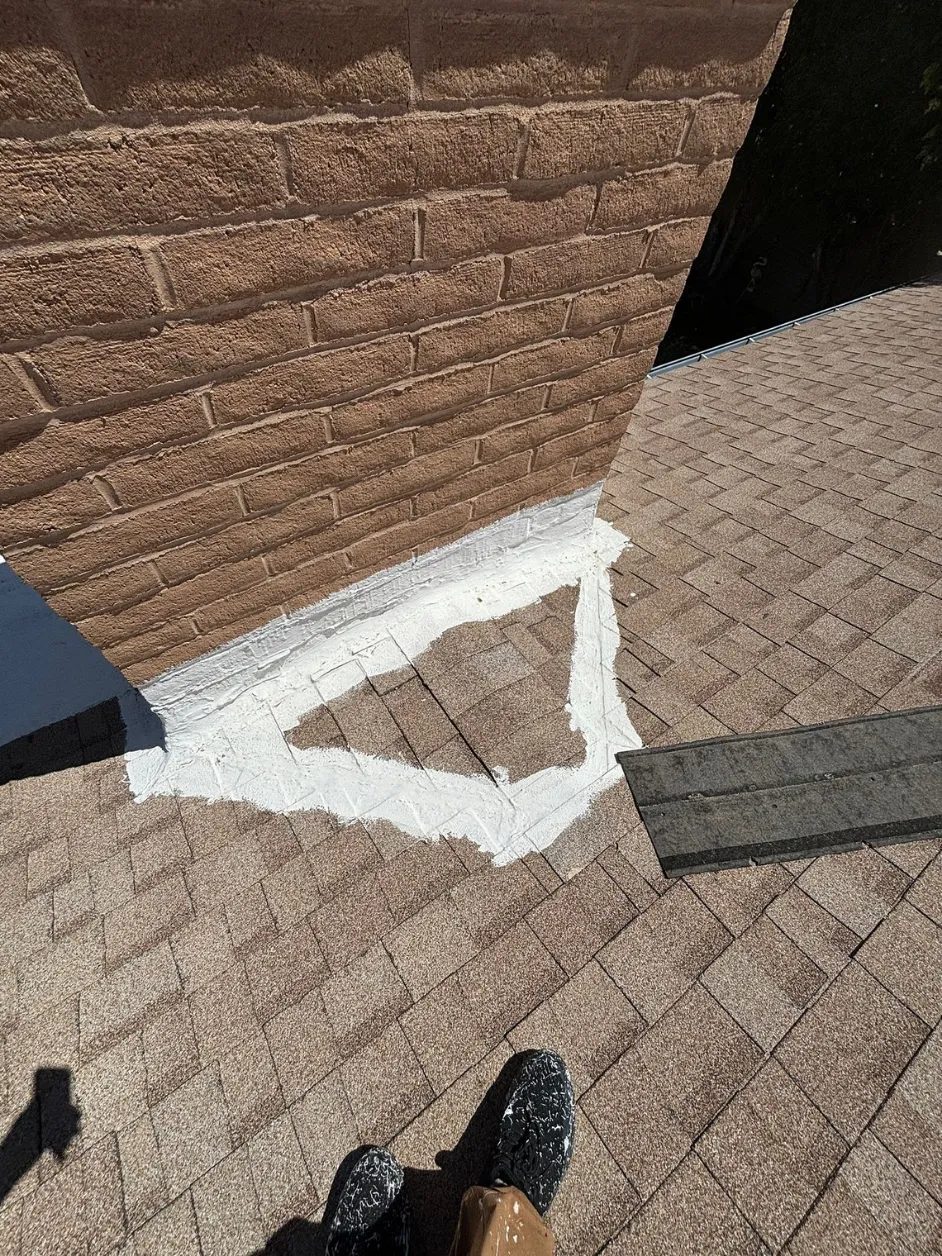 Roof sealant smeared around the base of a brick chimney in place of proper flashing