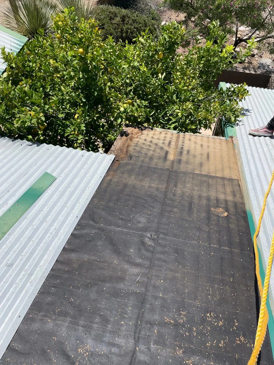 Metal panels lifted away, exposing the aged underlayment beneath