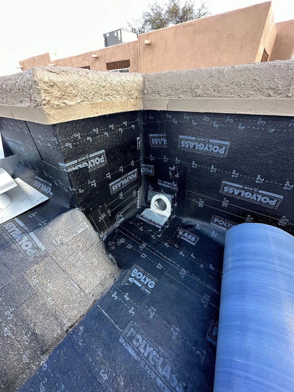 A new scupper outlet set into fresh Polyglass membrane at a parapet corner