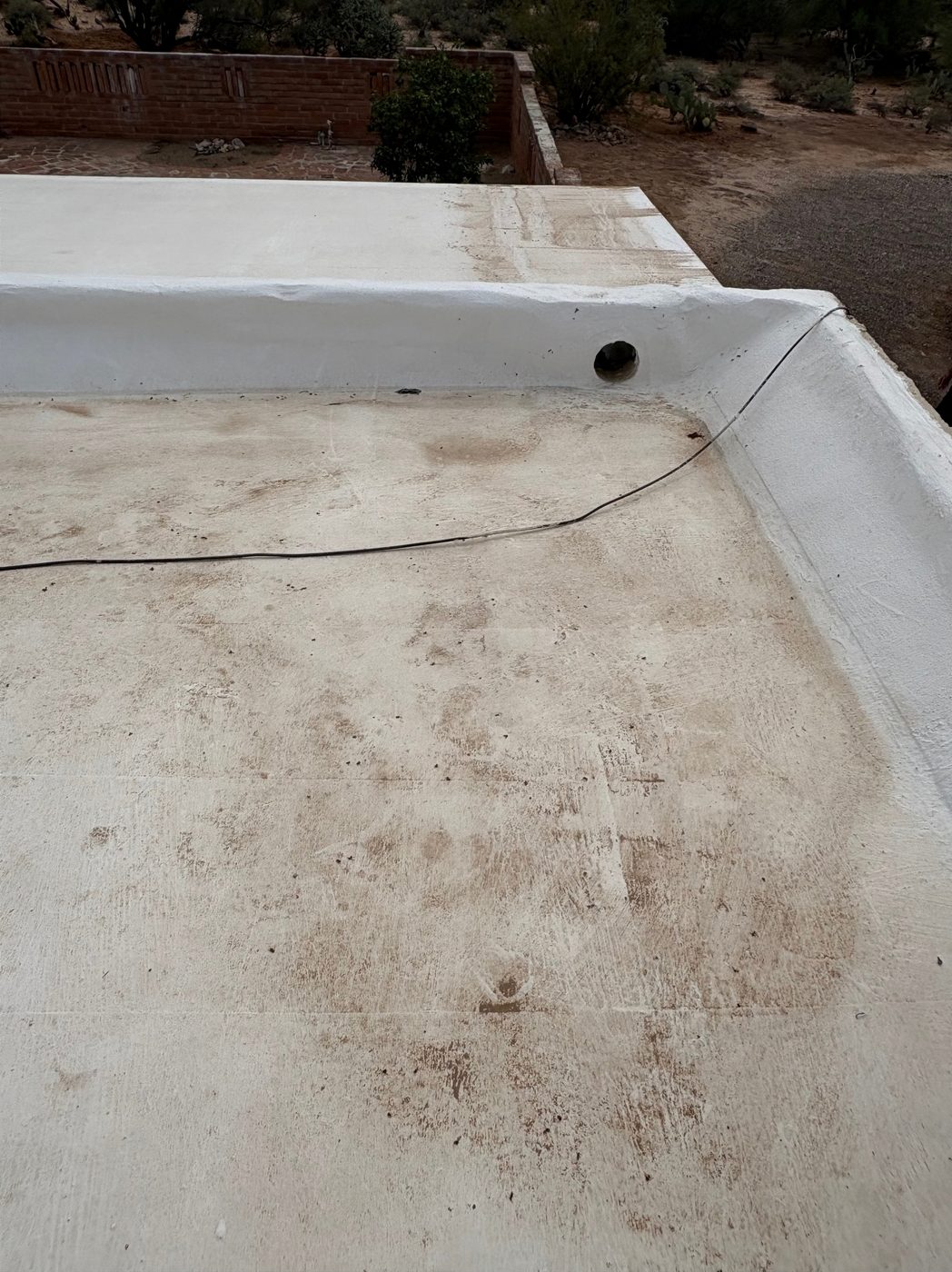 Standing-water staining marking a low ponding area on a Tucson flat roof before repair