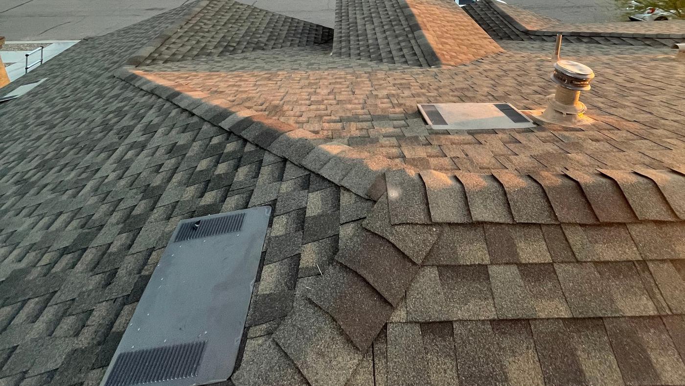 Roof vents and flashings beside a shingle ridge cap junction.