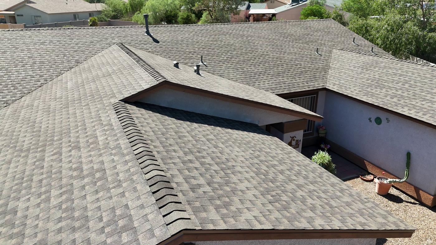 Elevated view of a finished shingle roof adjoining a modified bitumen flat roof.