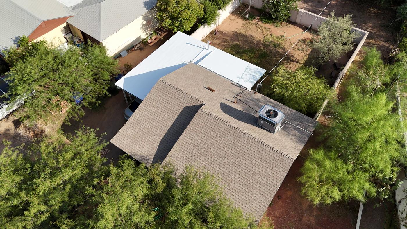 Aerial view of a finished shingle roof with an adjoining coated flat roof.