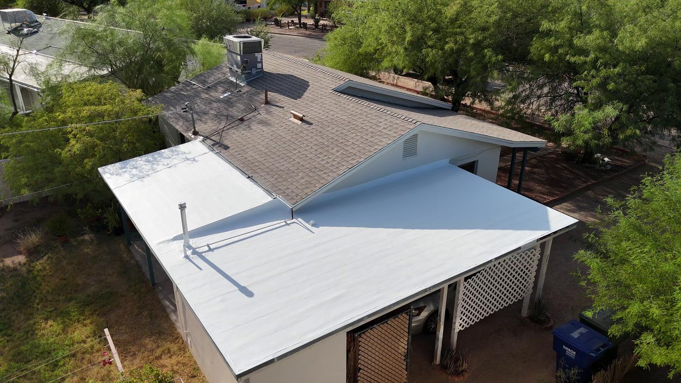 Finished shingle roof beside a flat roof with white roof coating.