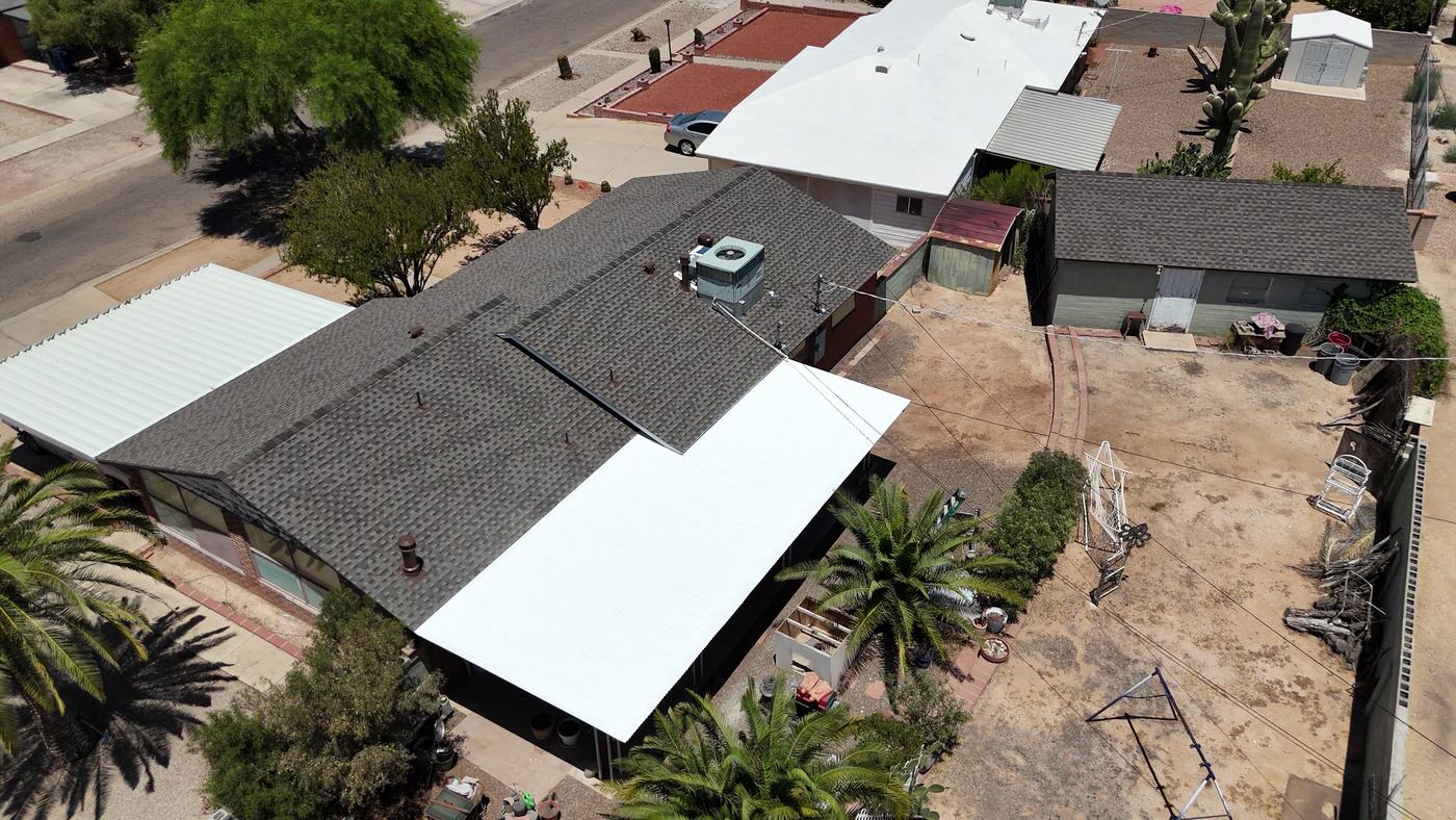 Overhead view of a finished shingle roof and a coated metal flat roof.