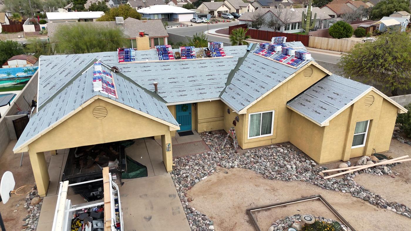 Aerial view of a shingle roof installation in progress with GAF FeltBuster underlayment exposed.