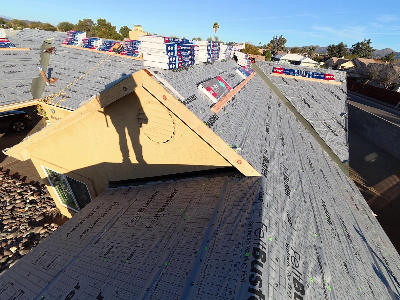 Shingle roof installation in progress showing GAF FeltBuster underlayment and exposed roof sheathing.