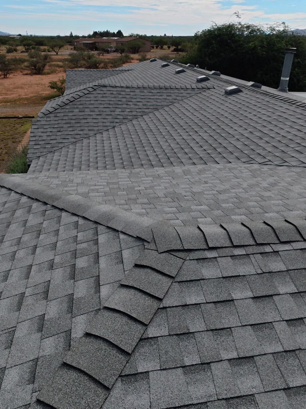 Finished asphalt shingle roof showing a ridge cap junction.