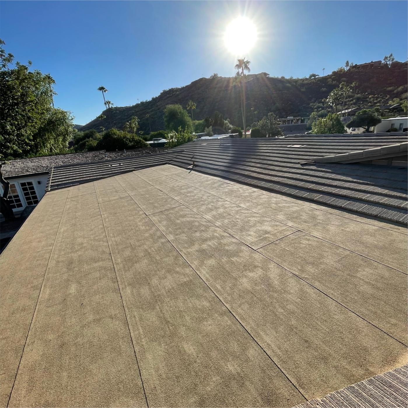 Modified bitumen flat roof adjoining a flat-profile concrete tile roof.