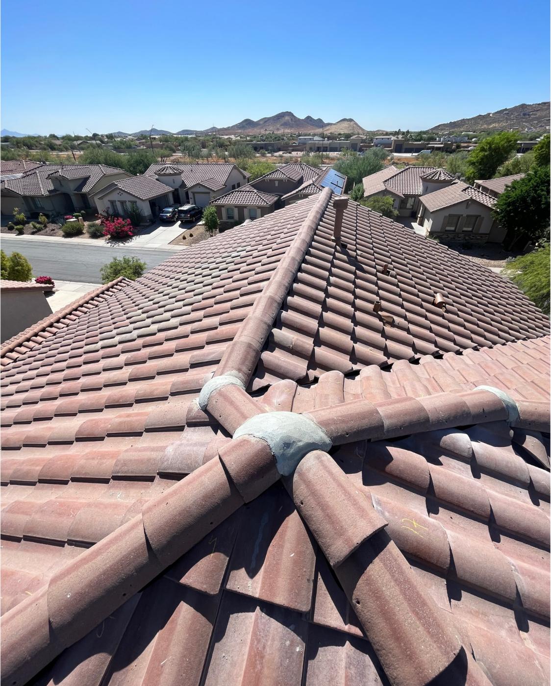 Finished concrete tile roof with intersecting ridges.