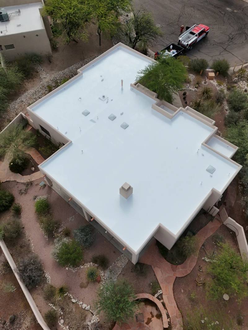 Aerial view of a Tucson flat roof finished with a bright white acrylic elastomeric coating, with the SolTerra Roofing truck parked at the curb