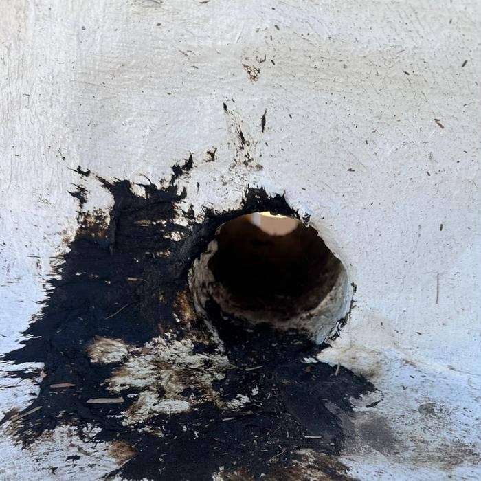 Roof drain on a Tucson flat roof surrounded by failed black mastic before repair
