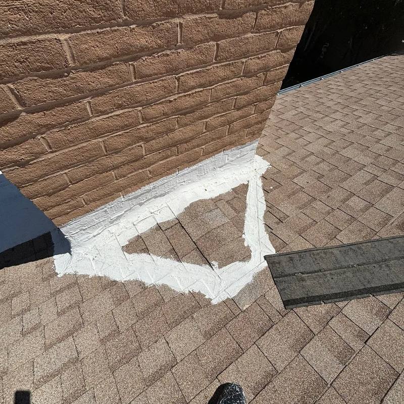 Roof sealant smeared around the base of a brick chimney in place of proper flashing
