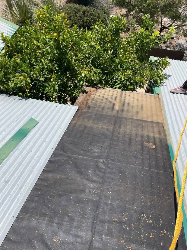 Metal panels lifted away, exposing the aged underlayment beneath