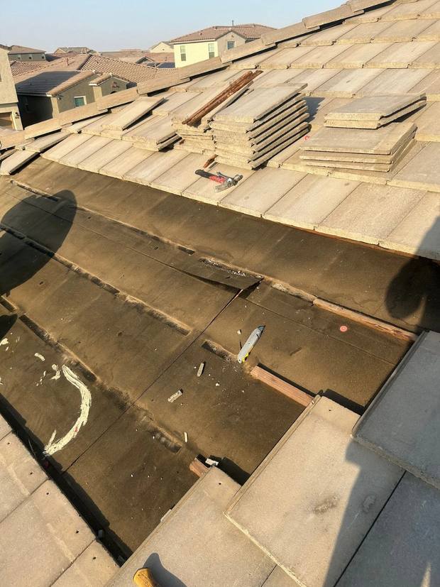 Concrete tile removed and stacked, exposing the worn underlayment beneath