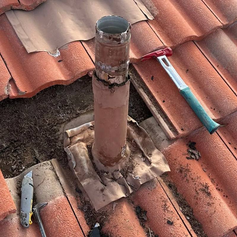 Deteriorated flashing around a roof vent pipe with the surrounding tile removed
